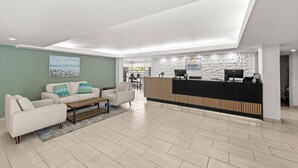 A modern hotel lobby with a reception desk, sofas, and a large painting on the wall. - Quality Inn Orlando Near International Drive (Orlando)