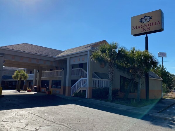 Welcome to Magnolia Inn, a two-story hotel with a covered entrance and balcony.