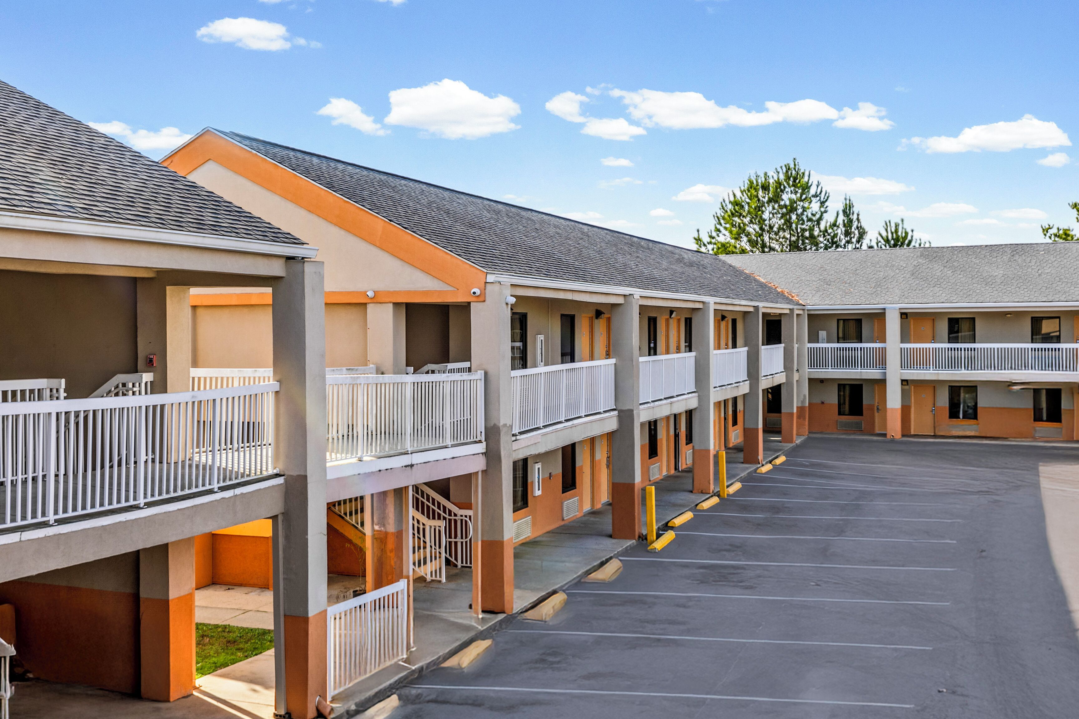 A motel with multiple floors, outdoor parking, and balconies.