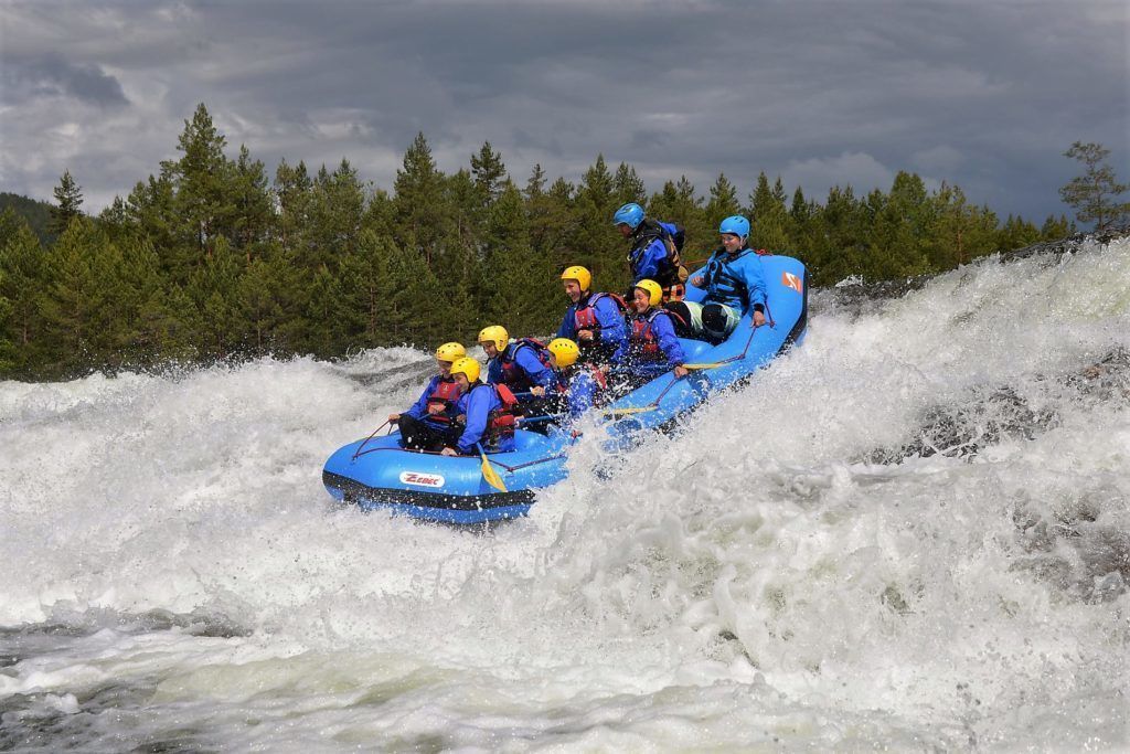 A group of people in a blue raft navigating through a river with white water.