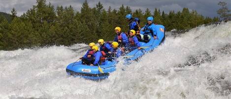 A group of people in a blue raft navigating through a river with white water.