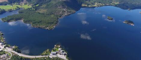 An aerial view of a lake surrounded by forested areas and a small settlement with roads and buildings.