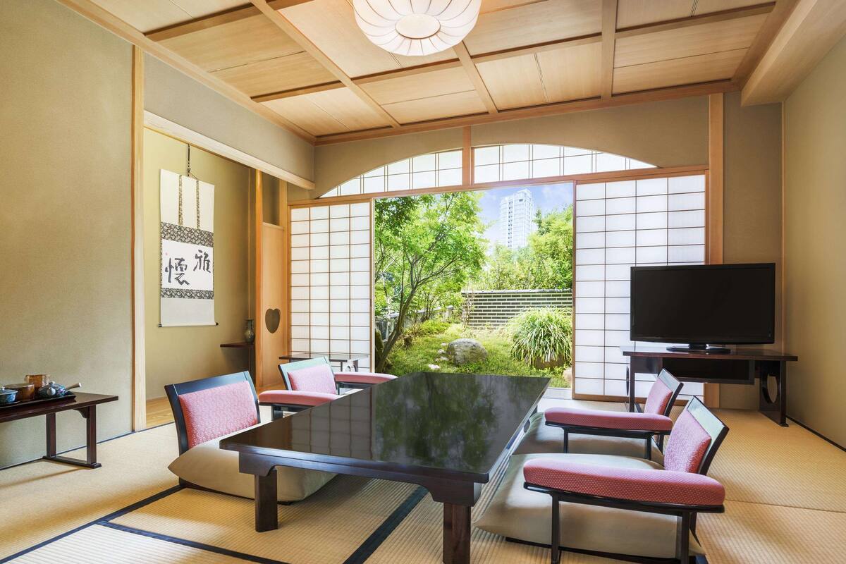 Une pièce de style japonais traditionnel, avec un sol recouvert de tatamis, une table basse et des paravents coulissants (shoji).