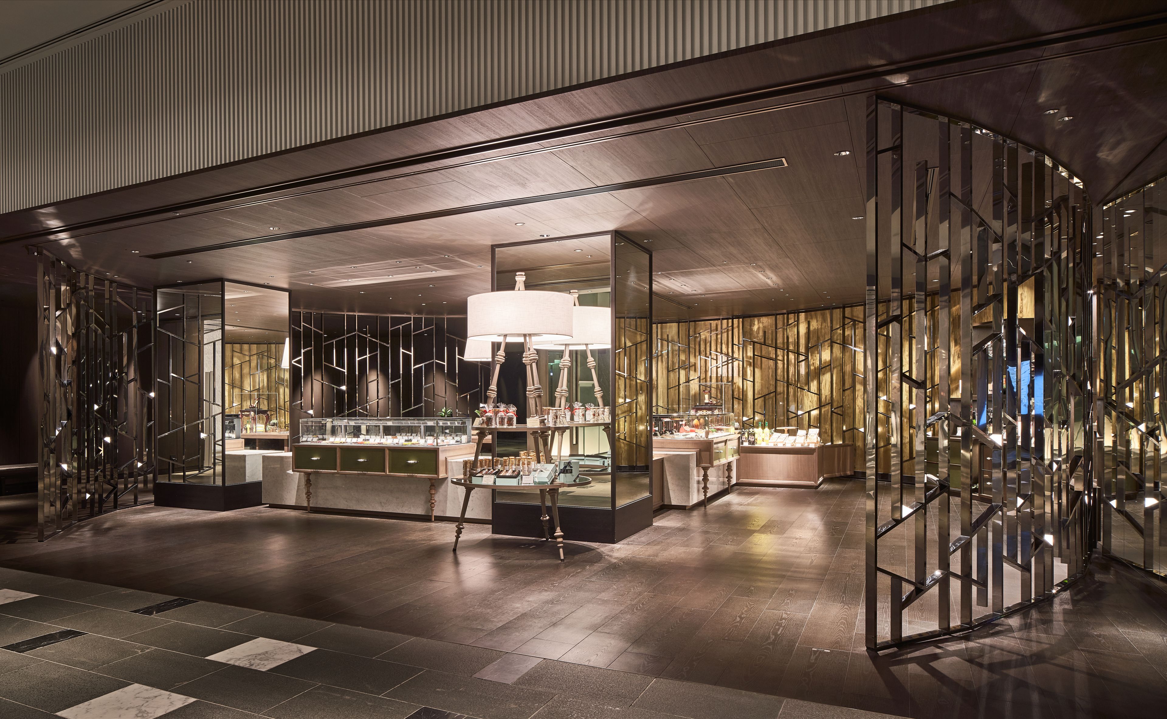 A modern interior with a central bar area, reflective glass partitions, and a polished wooden floor.