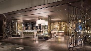 A modern interior with a central bar area, reflective glass partitions, and a polished wooden floor.