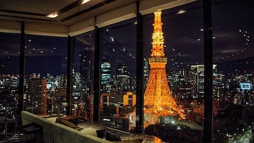 A high-rise interior with large windows overlooking a cityscape featuring a lit tower.