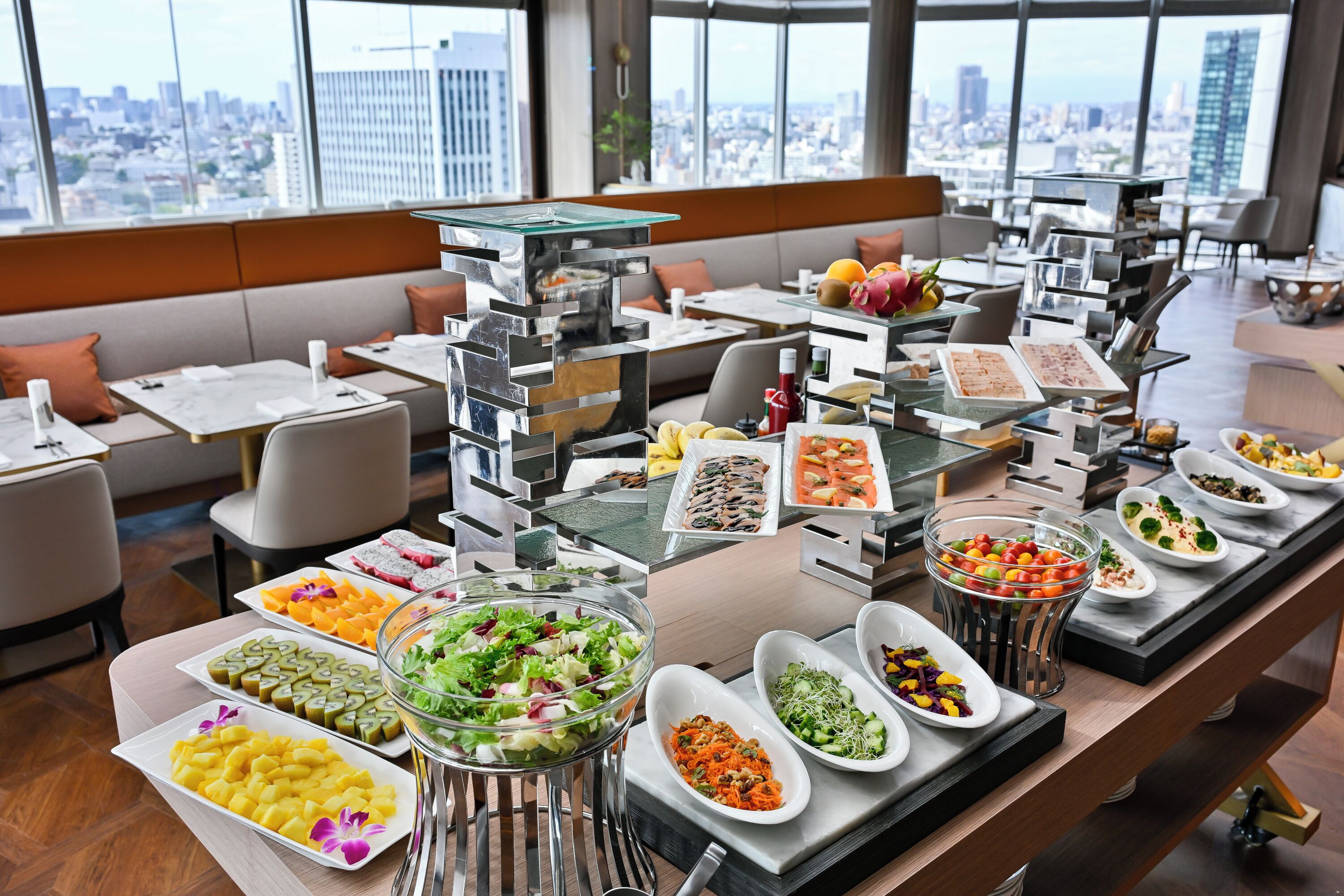 Un buffet est installé dans un hôtel moderne, offrant une variété de plats et une vue sur la ville.