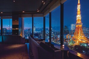 Una habitación de hotel moderna con amplios ventanales que ofrecen vistas a la Torre Eiffel de noche.