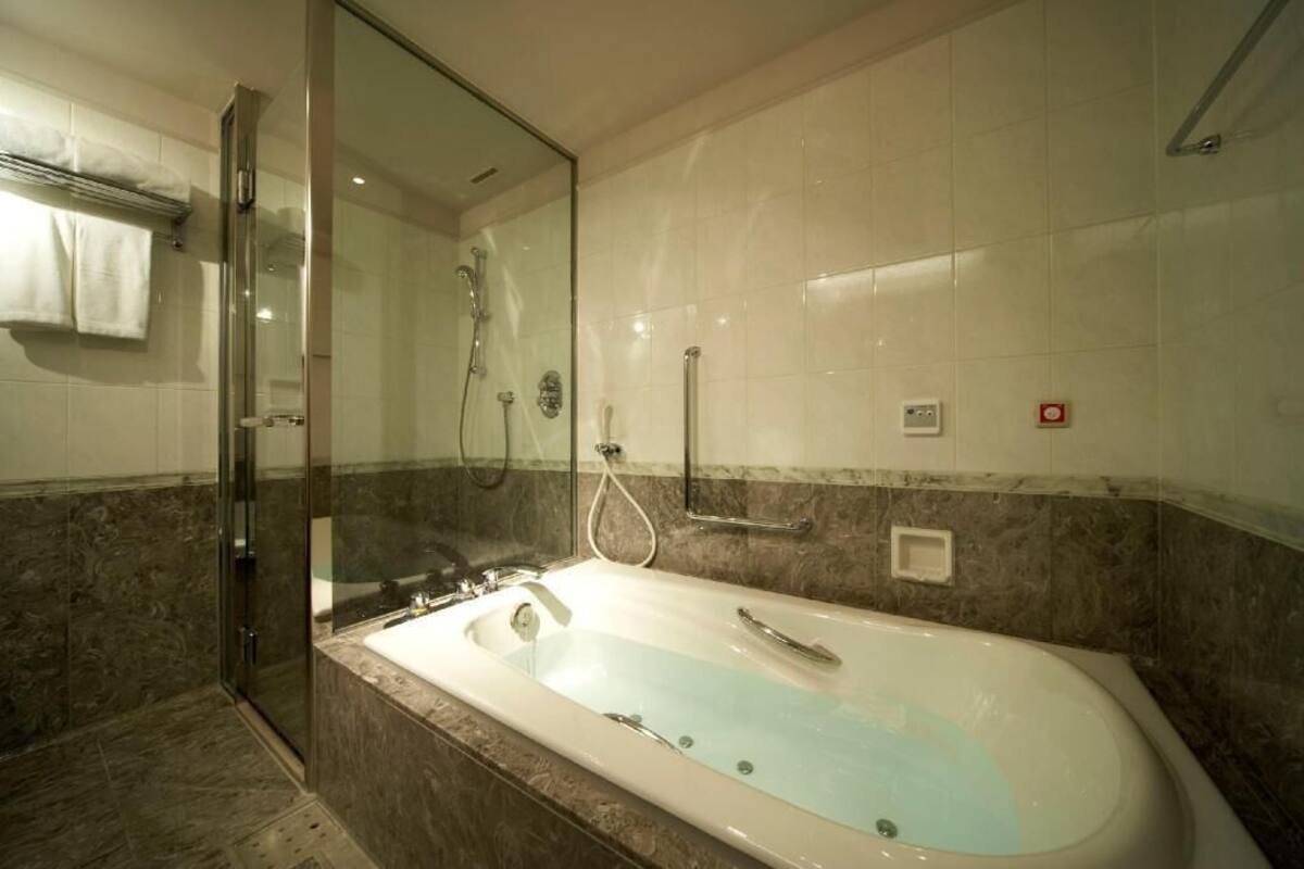 Une salle de bain dotée d’une douche à parois de verre, d’une baignoire sur pieds et de murs en marbre.