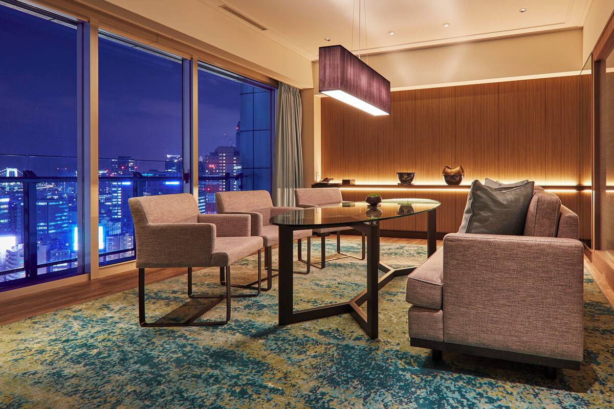 Une chambre d’hôtel moderne avec vue sur la ville, une table ronde en verre et un mobilier contemporain.