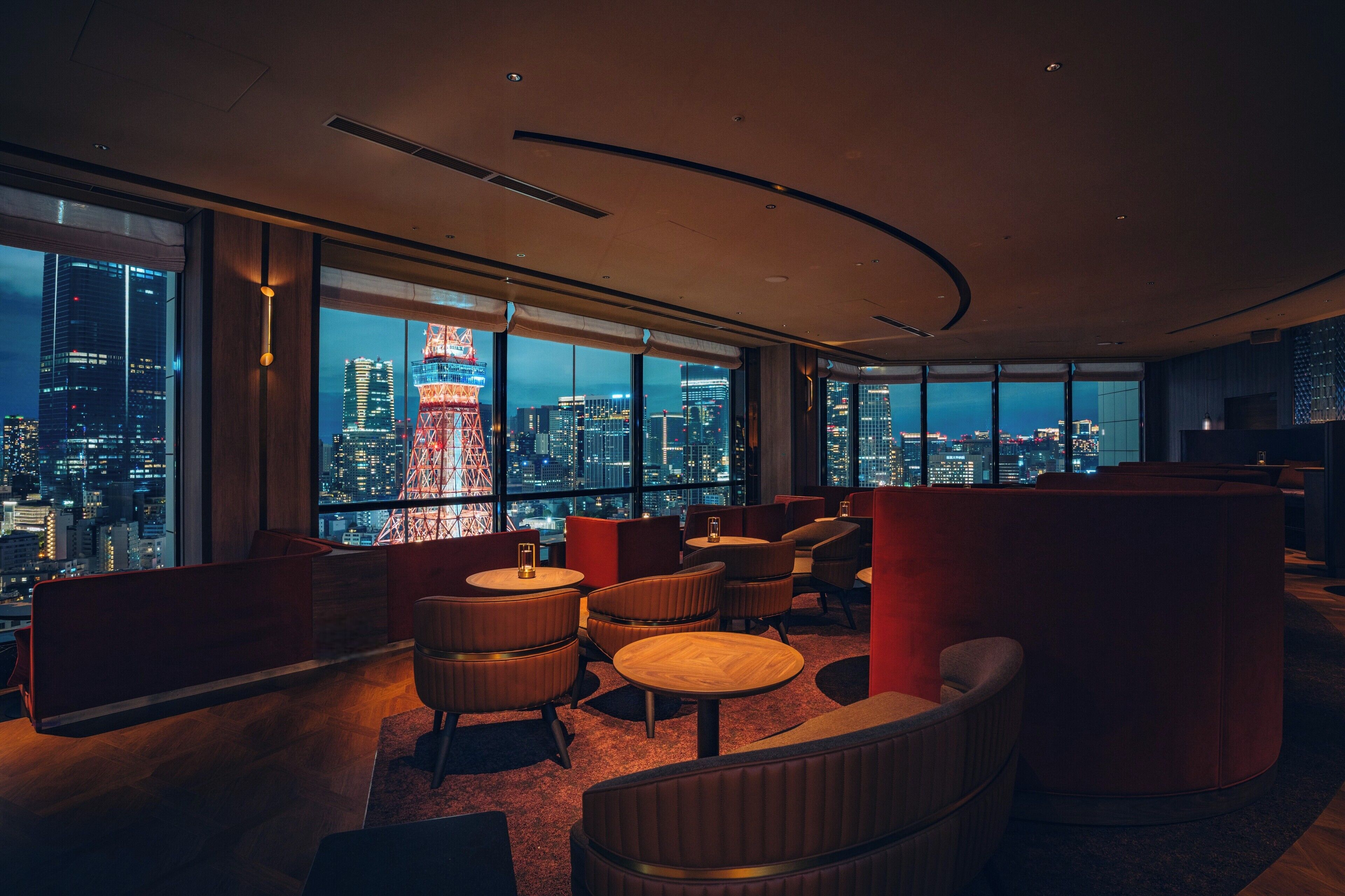 Un salón moderno con amplios ventanales que ofrecen vistas a la ciudad, incluyendo una torre destacada.
