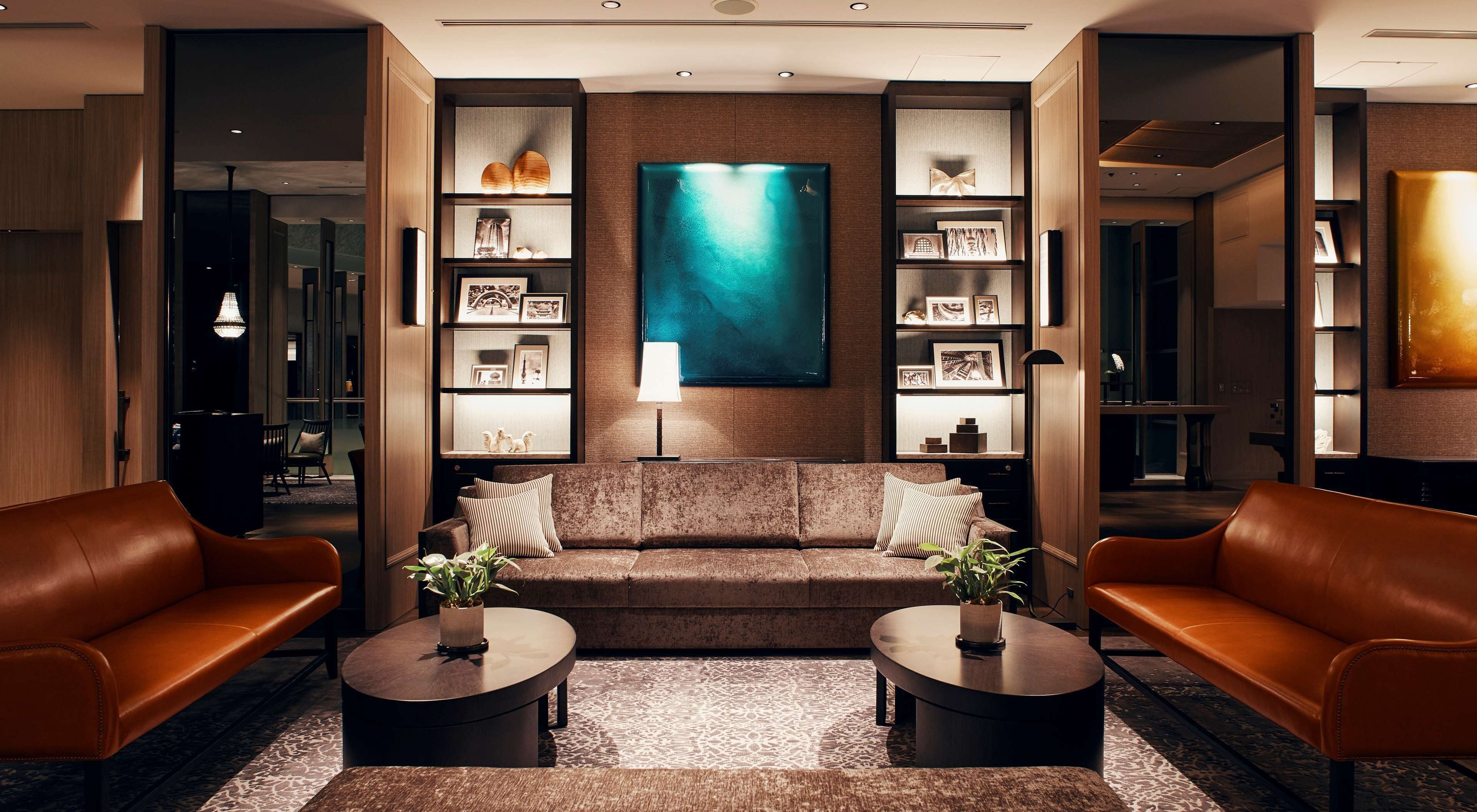 Een moderne woonkamer met een bruine bank, twee ronde salontafels en een groot abstract schilderij aan de muur.