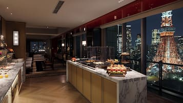 A modern hotel room with a marble breakfast bar, a city view, and a red accent wall.