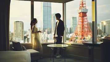 A hotel room with a large window offering a view of a cityscape and a prominent red tower.