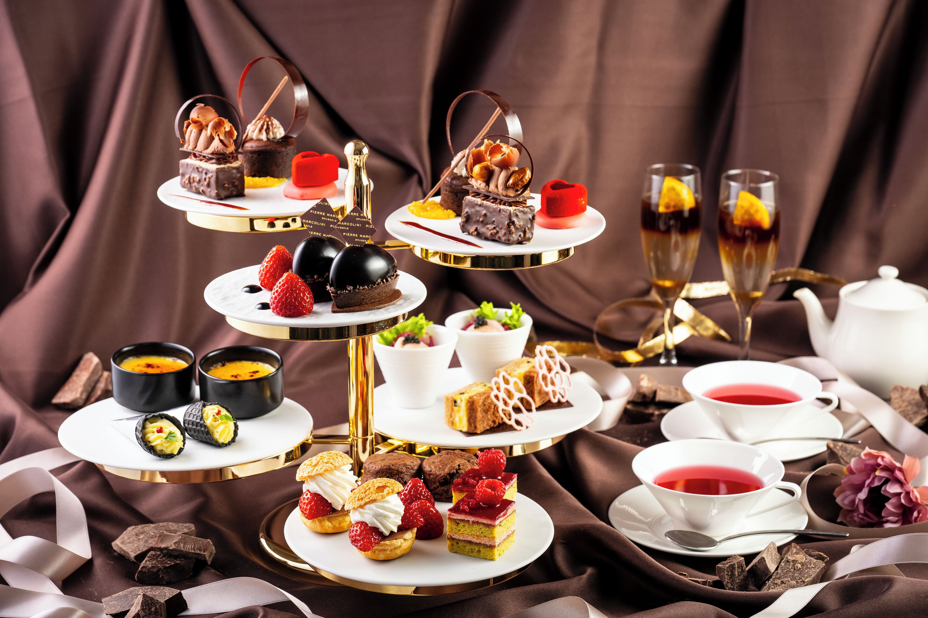 A multi-tiered dessert display with various pastries and beverages.