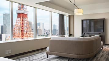 Une chambre d’hôtel avec une grande fenêtre, un canapé, une télévision et une vue sur la ville.