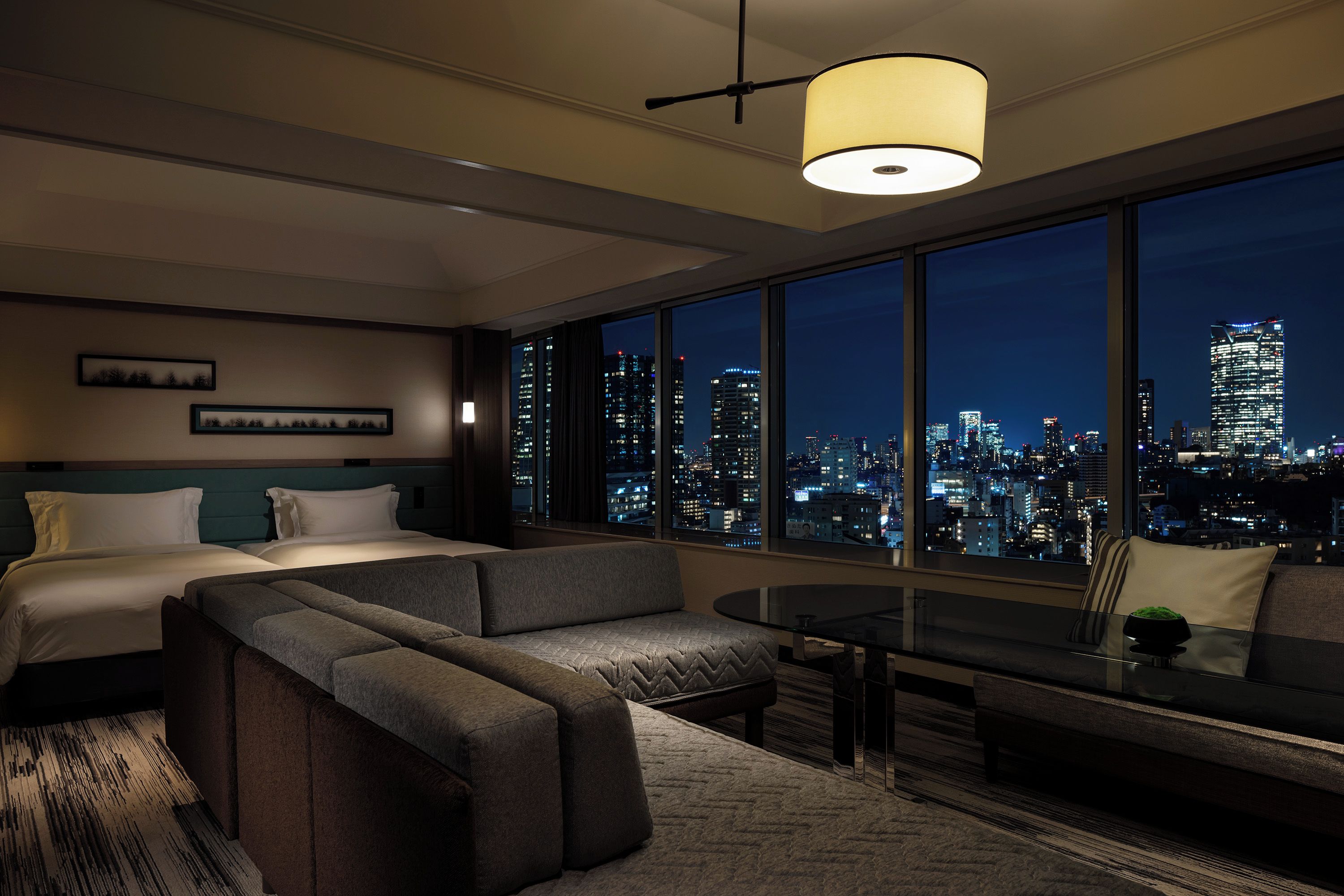 Ein modernes Hotelzimmer mit Bett, Sofa und Blick auf die Stadt.