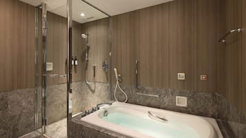 A modern bathroom with a glass-enclosed shower, a freestanding bathtub, and marble flooring.