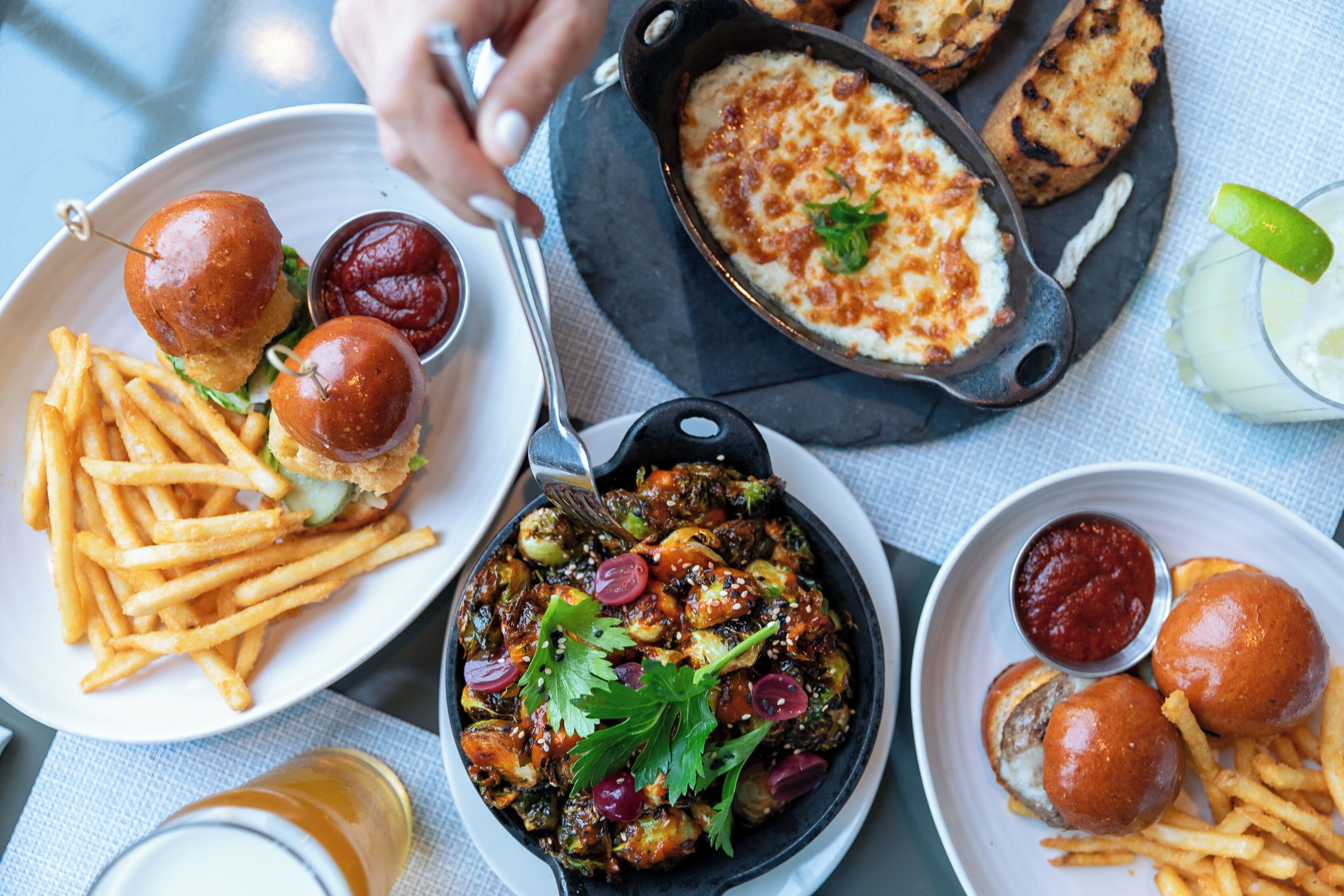 A meal with burgers, fries, and a skillet dish, served on a table.
