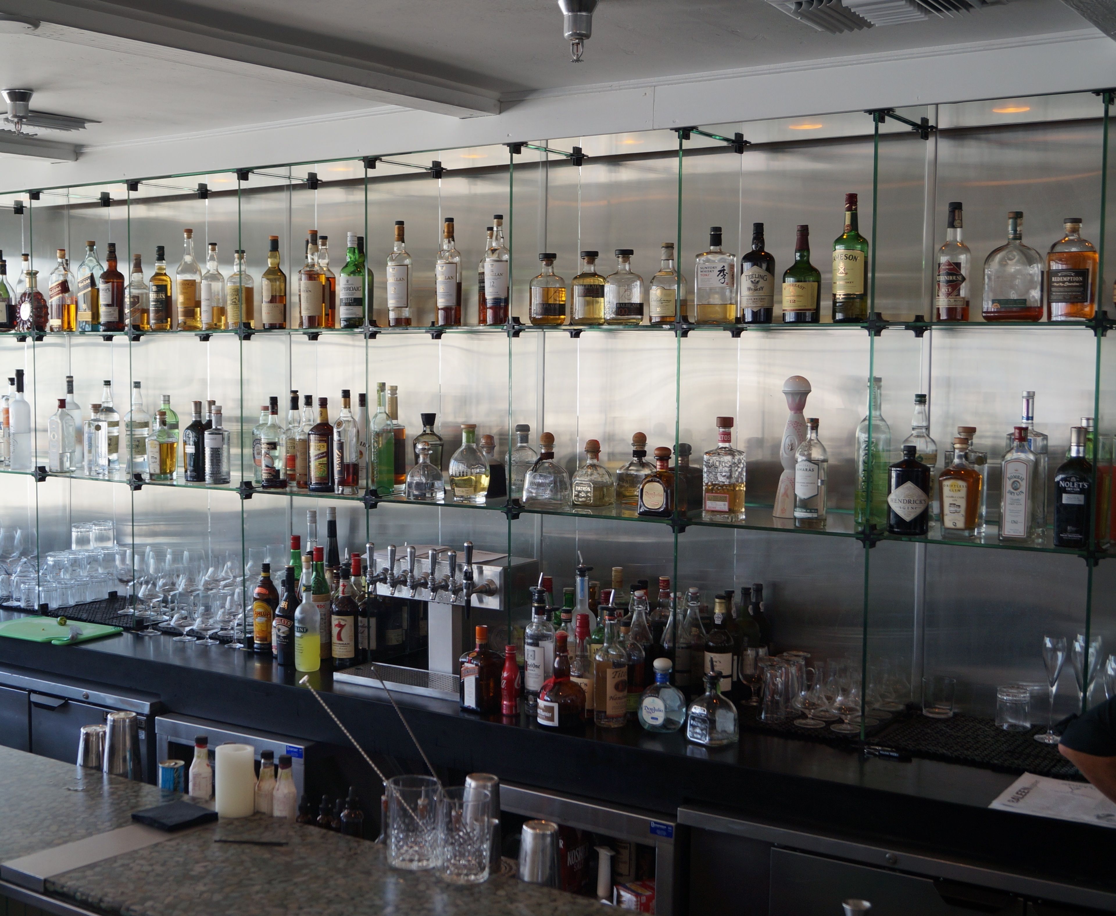 A bar area with shelves of various liquor bottles and glasses.
