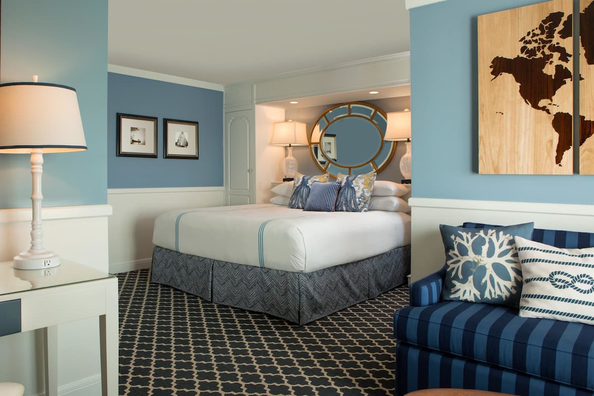 A bedroom with a bed, bedside lamps, a dresser, a mirror, and a map on the wall.