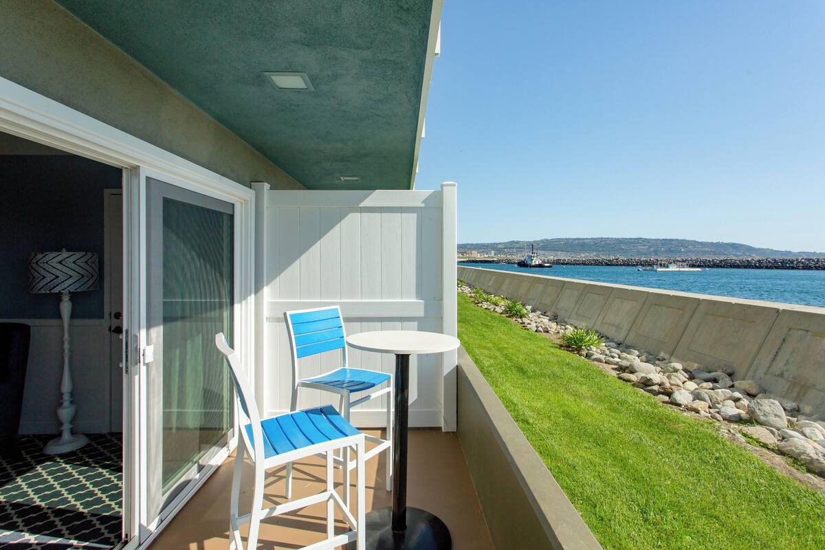 A balcony with a white door, a blue chair, and a small table.