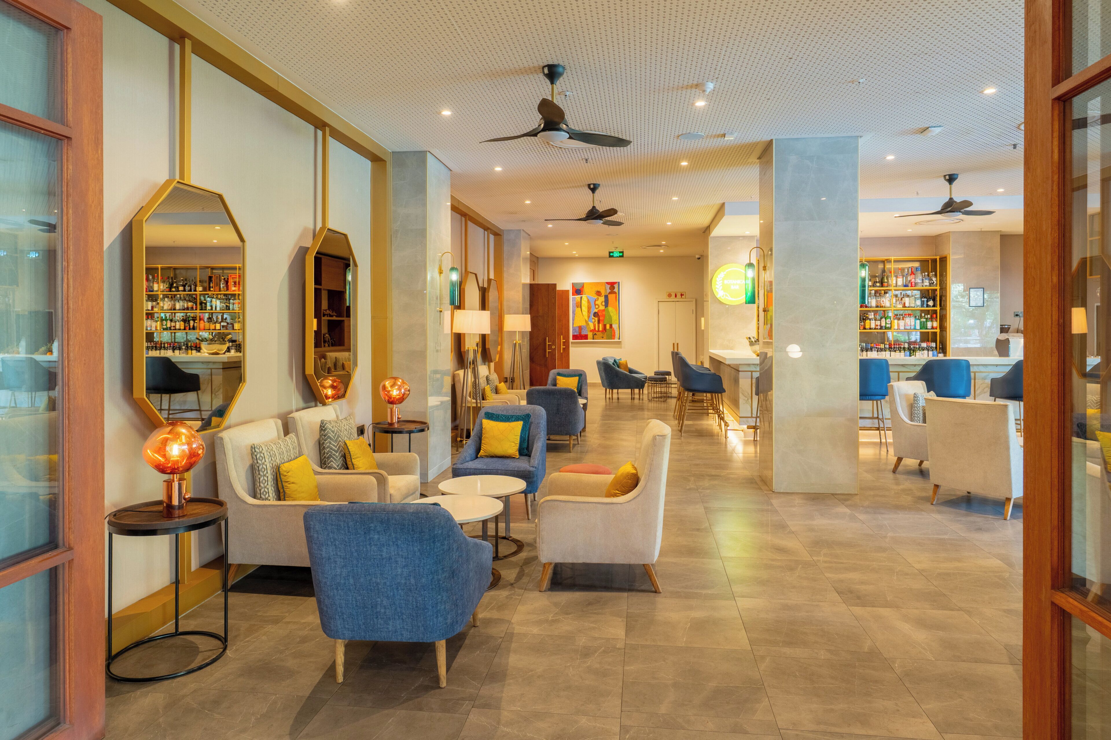 Un vestíbulo de hotel con áreas de descanso, un bar y una recepción.