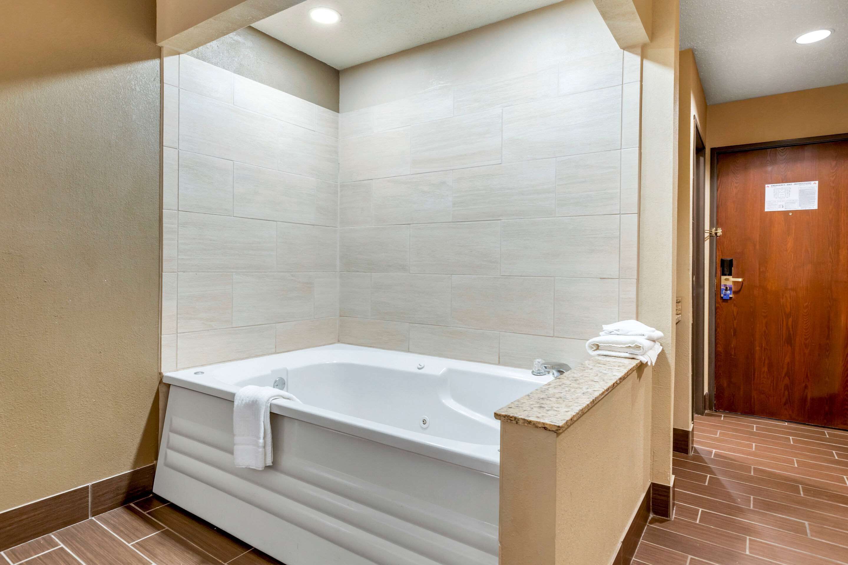 A modern bathroom with a freestanding bathtub, tiled walls, and a wooden door.