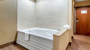 A modern bathroom with a freestanding bathtub, tiled walls, and a wooden door.
