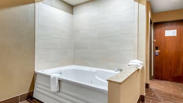 Une salle de bain moderne avec une baignoire sur pieds, des murs carrelés et une porte en bois.