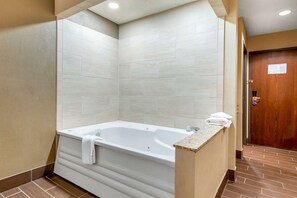 A modern bathroom with a freestanding bathtub, tiled walls, and a wooden door.