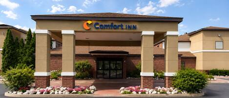 Eingang eines Comfort Inn Hotels mit Ziegelaußenwand, überdachter Eingangszone und bepflanzten Blumenbeeten.