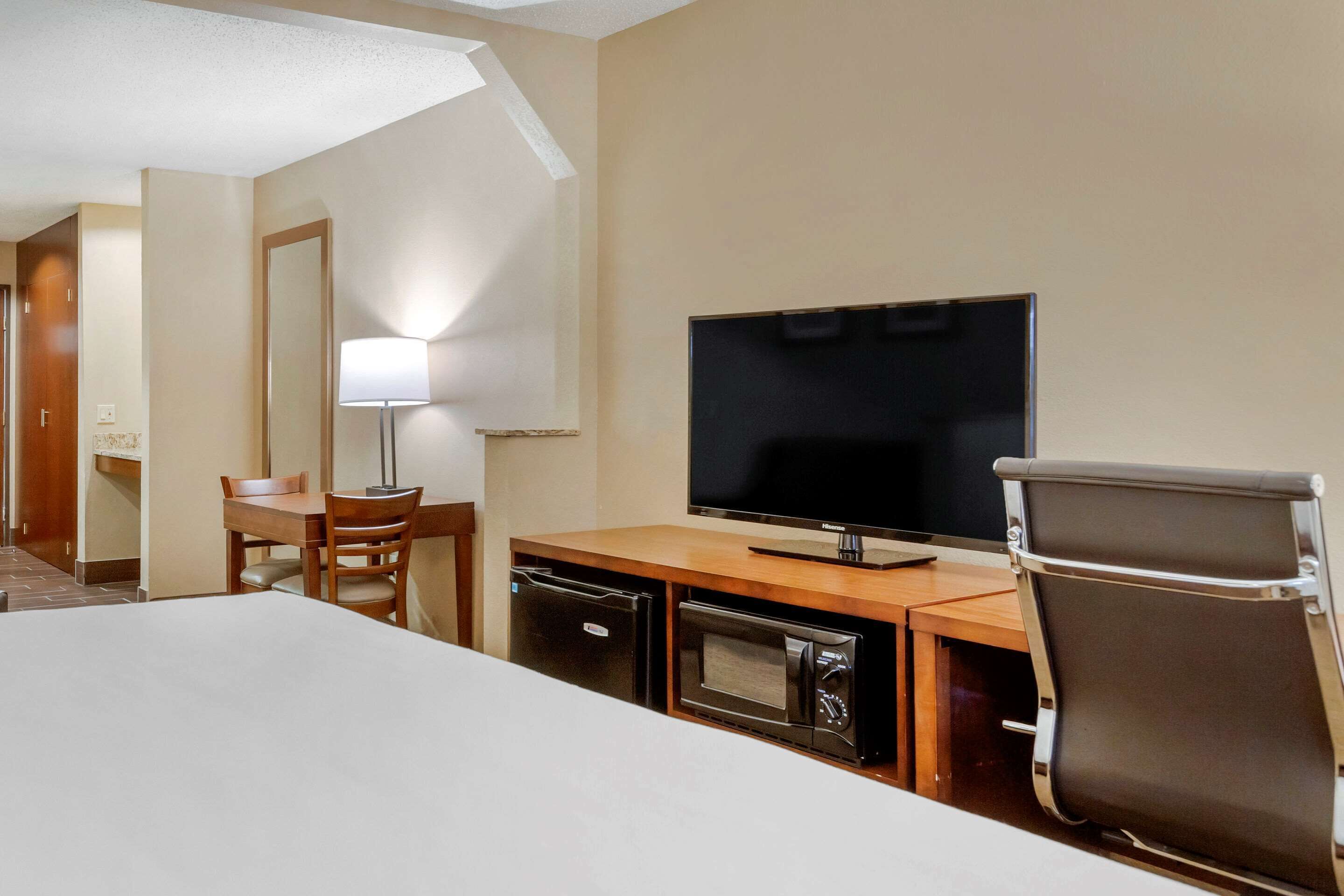 A hotel room with a bed, a desk with a television, a lamp, and a microwave.