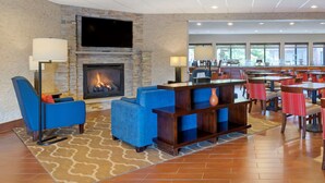 A lobby with a stone fireplace, blue seating, and a bar area.
