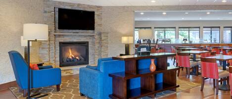 A lobby with a stone fireplace, blue seating, and a bar area.