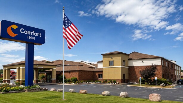 A Comfort Inn hotel with a flagpole, a parking lot, and a building entrance.
