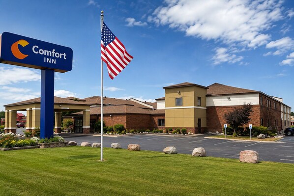 A Comfort Inn hotel with a flagpole, a parking lot, and a building entrance.