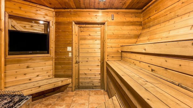 A wooden sauna with benches and a television screen.