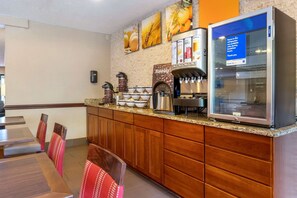 A breakfast area with a coffee machine, a refrigerator, and a sign indicating items are refrigerated.