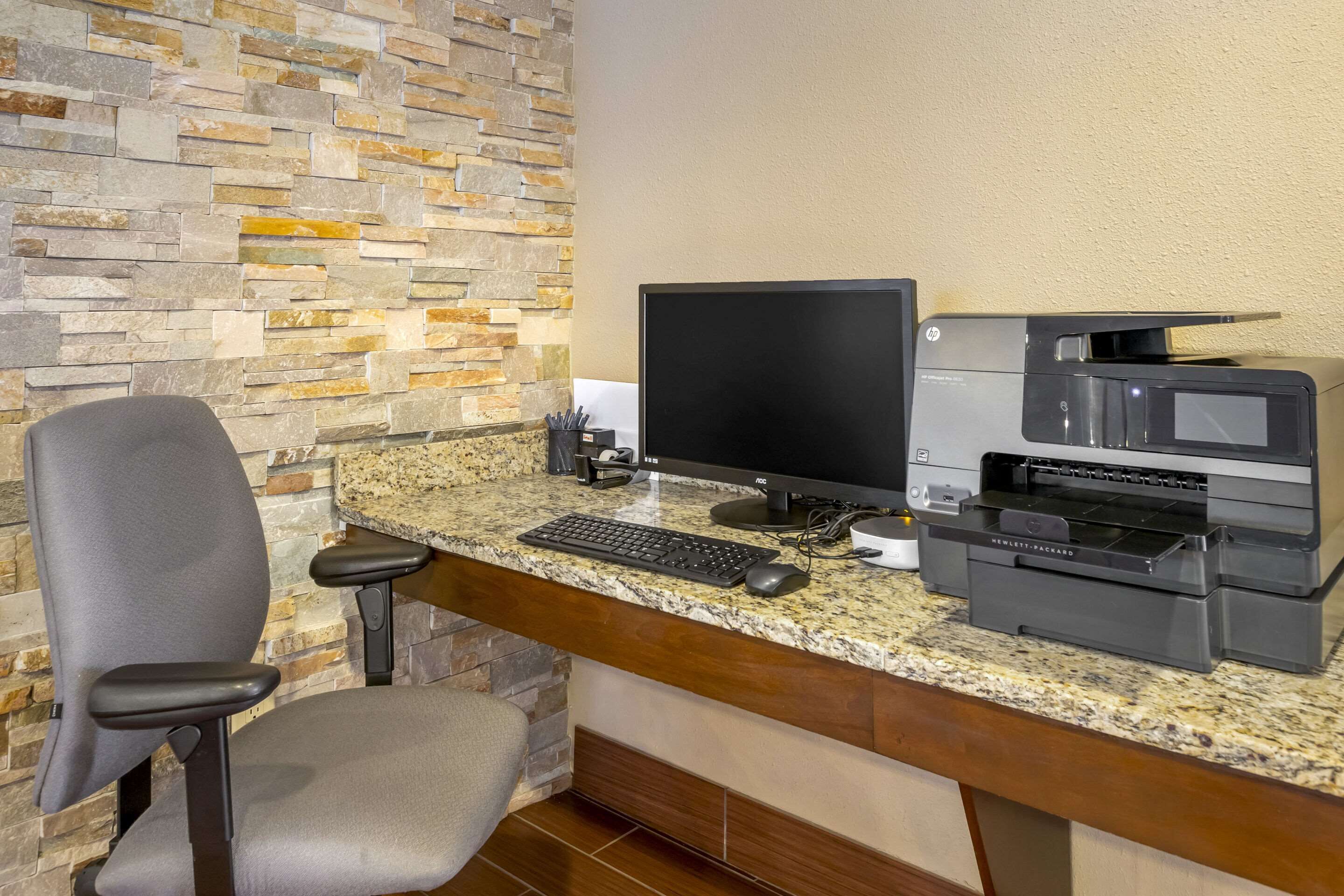 A workspace with a desktop computer, a printer, and a chair.