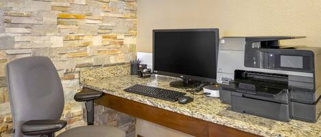 A workspace with a desktop computer, a printer, and a chair.