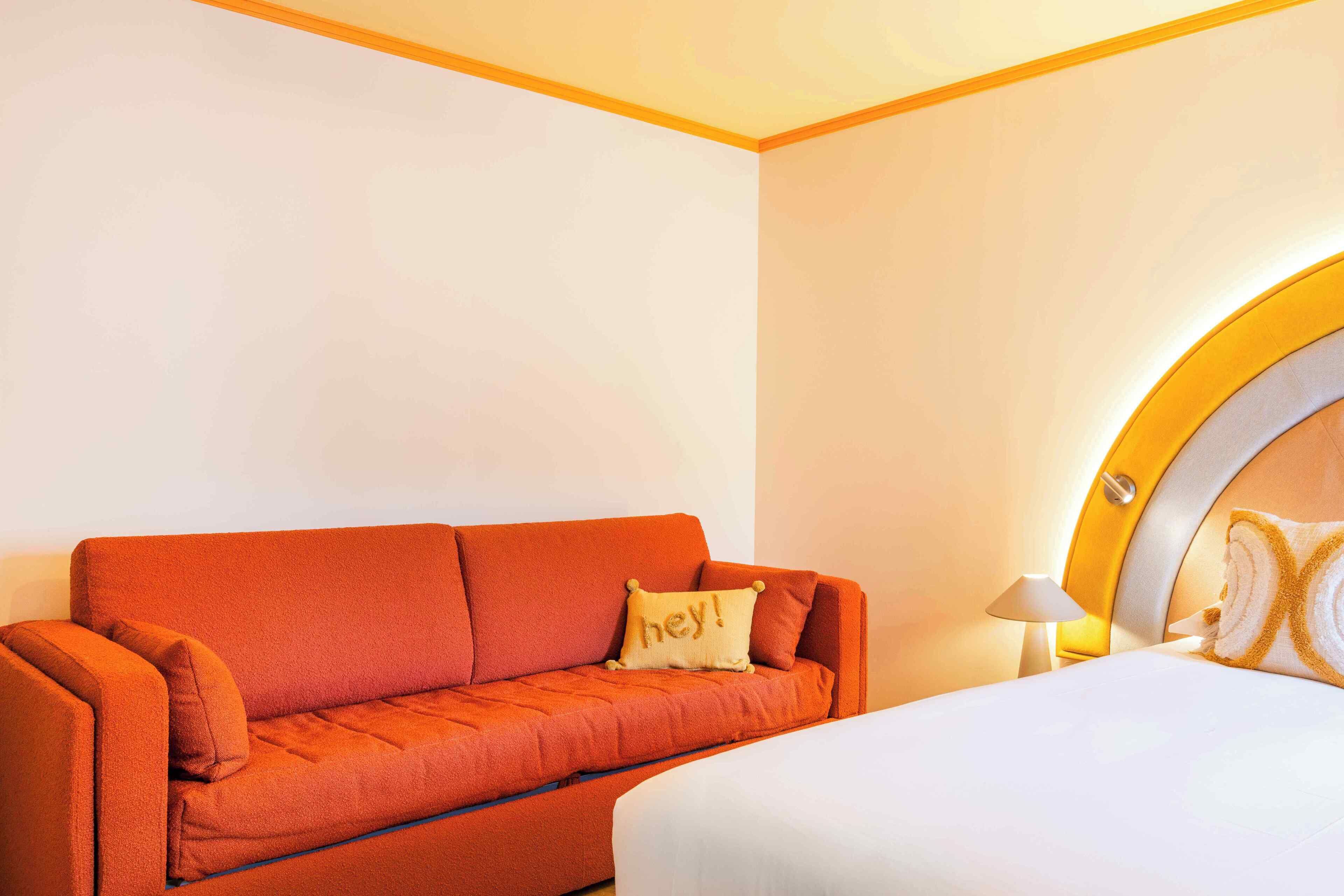Een kamer met een bank, een bed en een lamp.