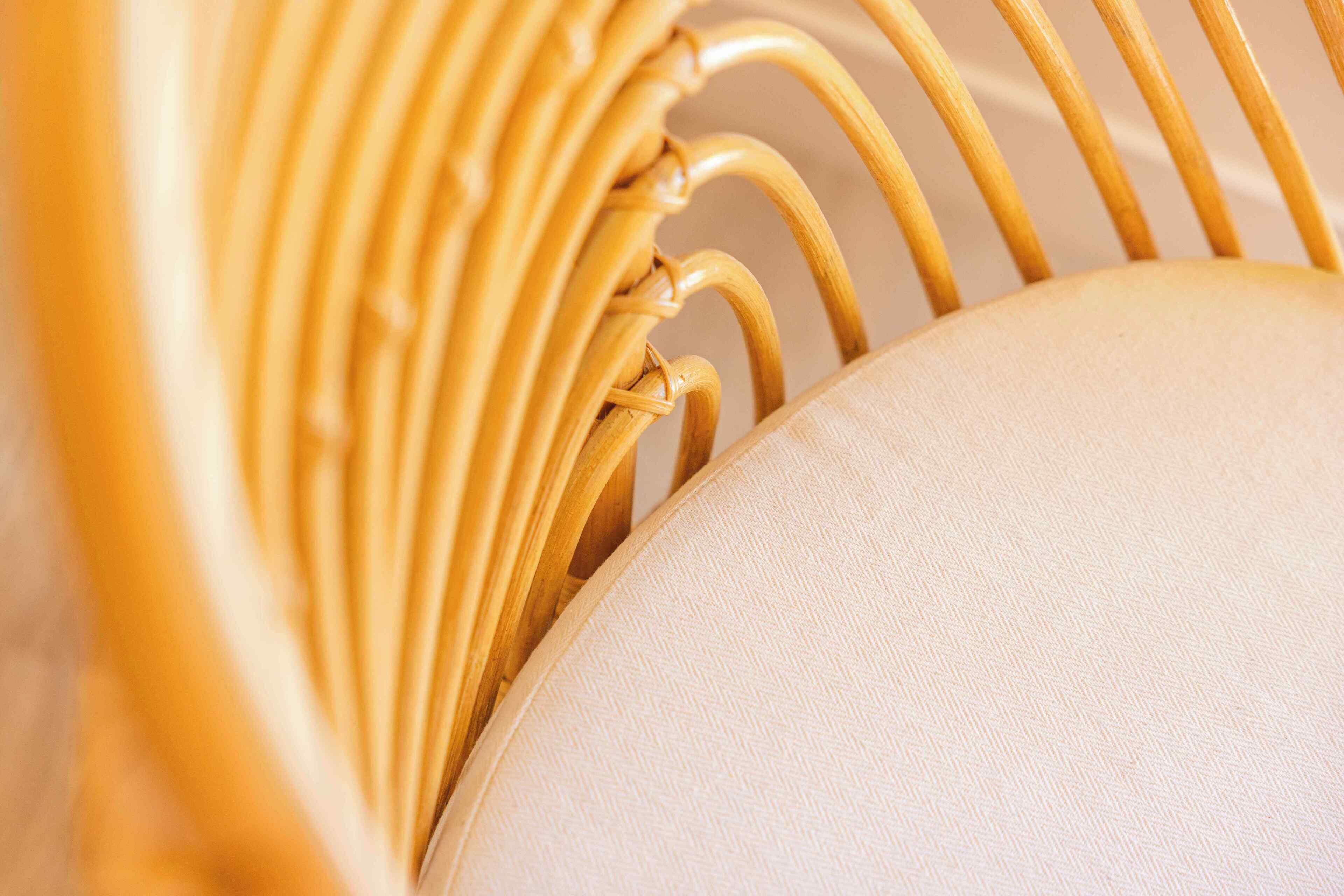 A close-up of a chair with a woven backrest and a cushioned seat.