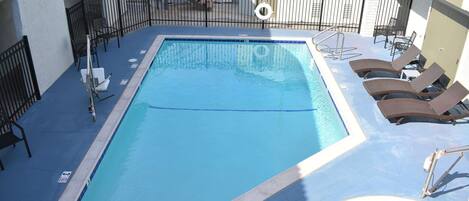 A swimming pool with a hot tub, lounge chairs, and a lifeguard stand.
