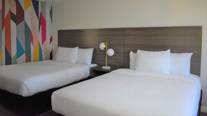 A hotel room with two beds, a modern headboard, and a colorful geometric wall design. - Signature Anaheim Maingate (Anaheim)