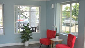 A room with two red chairs, a small white table, and a potted plant. - Signature Anaheim Maingate (Anaheim)