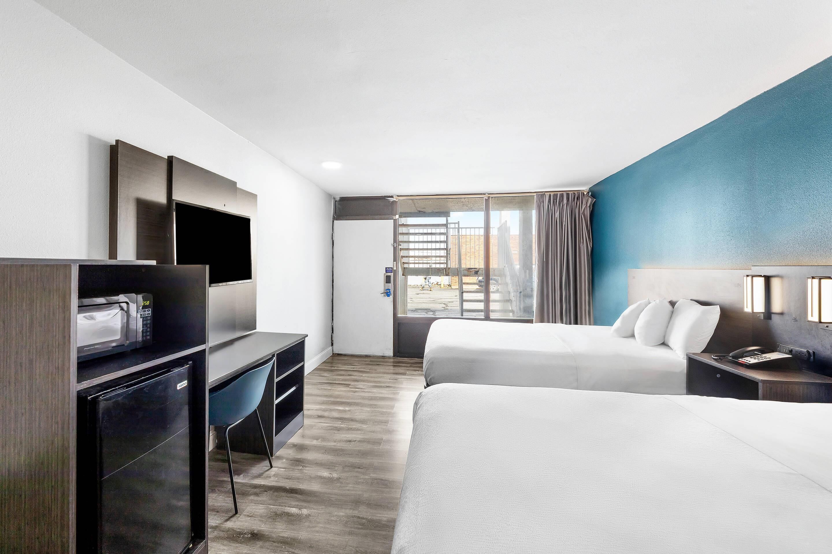 A modern hotel room with a bed, desk, and a TV.