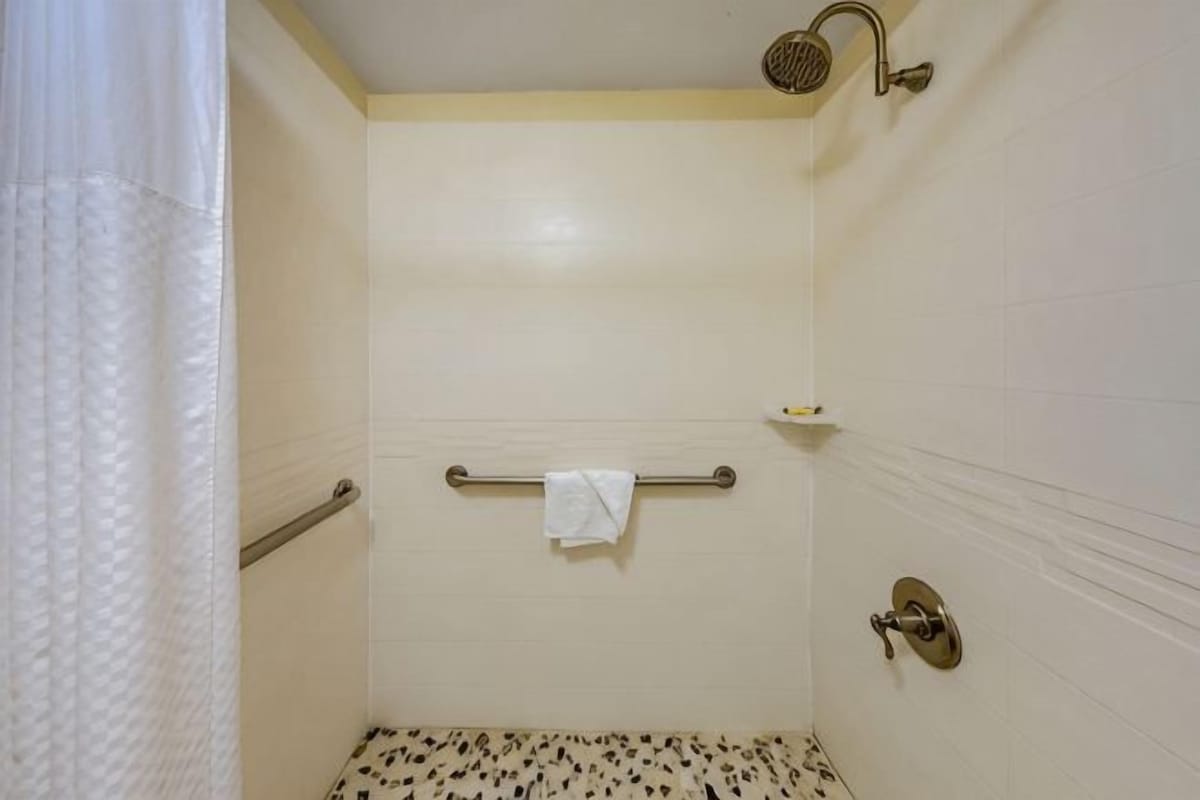 A small, enclosed shower area with a showerhead, towel rack, and a towel hanging on the wall.