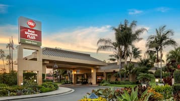 Welcome to Best Western Plus South Coast, where a covered walkway leads to the main building with a flat roof and columns.