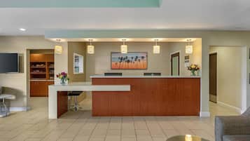 A reception area with a wooden reception desk, a TV mounted on the wall, and a painting above the desk.